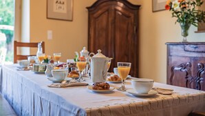 A breakfast table set with various breakfast items, including pastries, a jug of orange juice, and a teapot. - GUEST HOUSE OSTAL CASSINIA  (Cassagne)