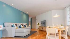 A modern living room with a sofa, dining table, and TV. - Santa Catarina Lively Apartment by Liiiving (Porto)