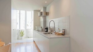 A modern kitchen with white cabinets, a stainless steel sink, and a window providing natural light. - Santa Catarina Lively Apartment by Liiiving (Porto)