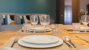 A dining table set with plates, glasses, and cutlery, with a sofa and cushions in the background. - Santa Catarina Lively Apartment by Liiiving (Porto)