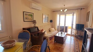 Una sala de estar con sofá, mesa de centro, televisor y zona de comedor con sillas y una mesa.