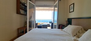 A hotel room with a bed, a small table, and a view of the sea through an open door. - A11 EDIFICIO OASIS 8D (Calpe)