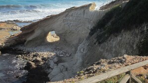 Un paisaje costero con una formación rocosa destacada que presenta un arco natural.