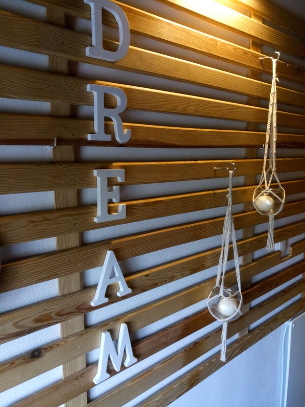 A wooden slat wall with the letters "DREAM" and a macrame hanging ornament.