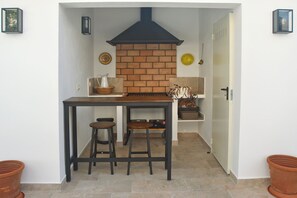 Une cuisine compacte avec un mur en briques, une hotte noire et deux tabourets.
