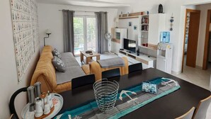 Uma sala de estar moderna com sofá, mesa de jantar e espaço de cozinha.
