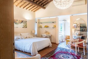Une chambre à coucher avec un lit, une table de chevet, une lampe et un élément décoratif mural. On y trouve également une chaise et une petite table avec un panier.
