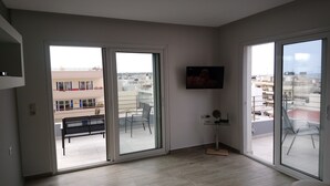 A modern apartment with large sliding glass doors, a flat-screen TV mounted on the wall, and a minimalist interior design. - Limena's penthouse apartment (Limenaw Hersonisou Crete)