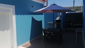 A patio with a table and chairs, a barbecue grill, and a blue wall.