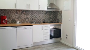 A kitchen with white cabinets, a dishwasher, a red coffee maker, a stove, and a patterned backsplash.