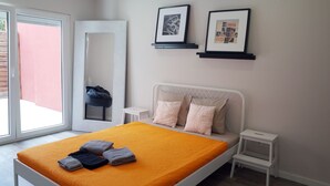 A bedroom with a bed, pillows, a nightstand, a framed picture, and a window.