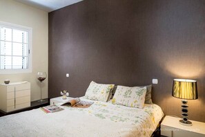 Une chambre à coucher avec un lit, des tables de chevet, une lampe, une fenêtre et une commode.