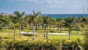Un campo de golf con palmeras y vista al océano.