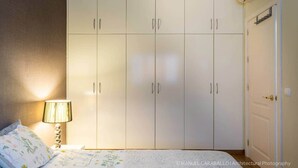 Un dormitorio con cama, mesita de noche, lámpara, armario y una puerta.