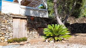 A stone building with a wooden door and a thatched roof structure.