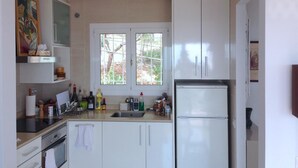Eine kleine Küche mit weißen Schränken, einer doppelten Spüle und einem Kühlschrank.
