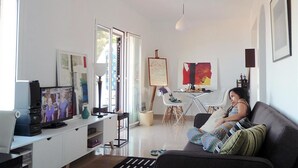 Ein modernes Wohnzimmer mit Flachbildfernseher, einer Couch, einem Couchtisch und einem Essbereich mit Stühlen.