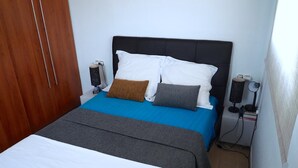 Ein Schlafzimmer mit Bett, Nachttisch, Lampe und Kleiderschrank.