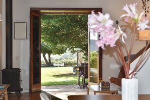 An open doorway leading to a garden with a table and chairs, a bench, and a fireplace.