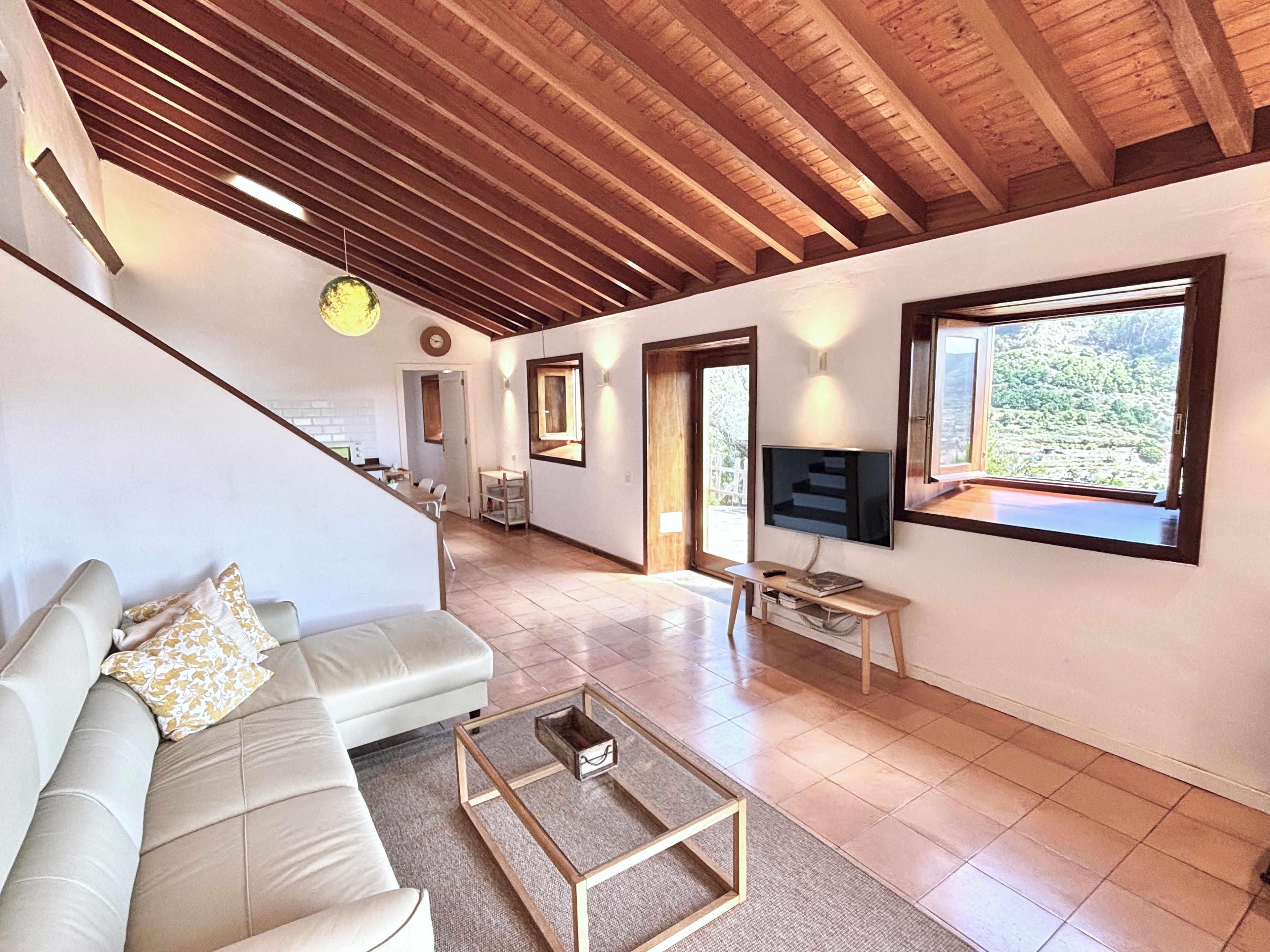A spacious living area with a sofa, a coffee table, and a TV mounted on the wall.