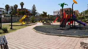 A playground with multiple slides and a paved walkway.