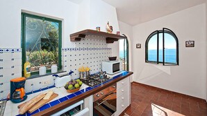 Una cocina con estufa, microondas y ventana con vista al mar.
