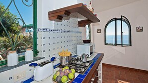 Una cocina con salpicadero de azulejos, estufa a gas, tostadora y un bol de fruta.