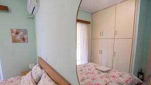 A bedroom with a bed, a wardrobe, and a painting on the wall. - Appartment 51 sq.m / Sandy beach + Int. Airport (Saronida)