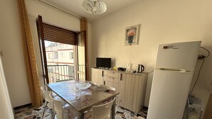 A small kitchen with a tiled floor, a refrigerator, a microwave, a sink, and a dining table with chairs. - Cozy and spacious apartment (Alghero)