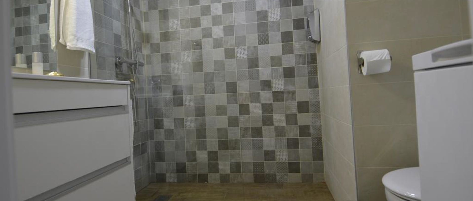 Un baño con un rebozado de azulejos a cuadros, un lavamanos blanco y un inodoro.