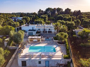 Una casa grande con piscina, rodeada de árboles y un paisaje montañoso.