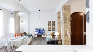 Uma sala de estar moderna com área de jantar, televisão e arte decorativa na parede.