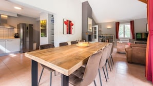 Una cocina moderna con comedor, una sala de estar con sofá y televisor.