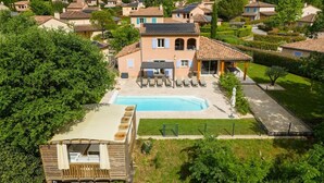 Una propiedad residencial con piscina, terraza de madera y jardín.