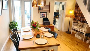 Een eetruimte met een houten tafel gedekt voor vier personen, omringd door stoelen, met een bloemenvaas op de tafel.