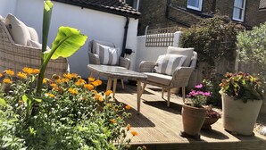 Een terras met rieten meubels, een tafel en potplanten.