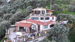A two-story house with a red-tiled roof, a balcony, and a patio area with outdoor furniture. - Sicilian villa nestled in a private olive grove near the Nebrodi Park (Reitano)