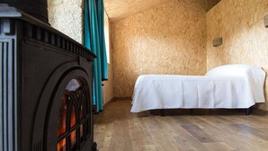 A room with a wooden floor, a bed with a white bedspread, and a fireplace with a dark-colored mantel. -   Casa do Comediante - Apartment 2 + 1 (San Xoán de Río)