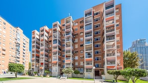 A multi-story residential building with balconies, a flat roof, and a clear blue sky.