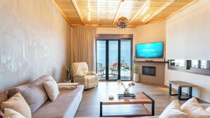 Een moderne woonkamer met een bank, fauteuils, een salontafel en een televisie.