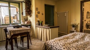 Une chambre à coucher de taille modeste, comprenant un lit, un petit bureau et une fenêtre donnant sur un balcon.