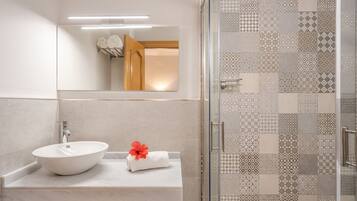 Un bagno moderno con un lavandino bianco, uno specchio e una doccia con piastrelle decorate.