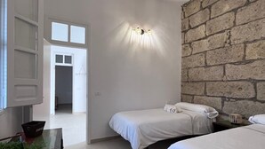 A bedroom with two beds, a brick wall, a white ceiling, and a door leading to another room. - Farmhouse Finca Delicias La Canaria (Alcalá)