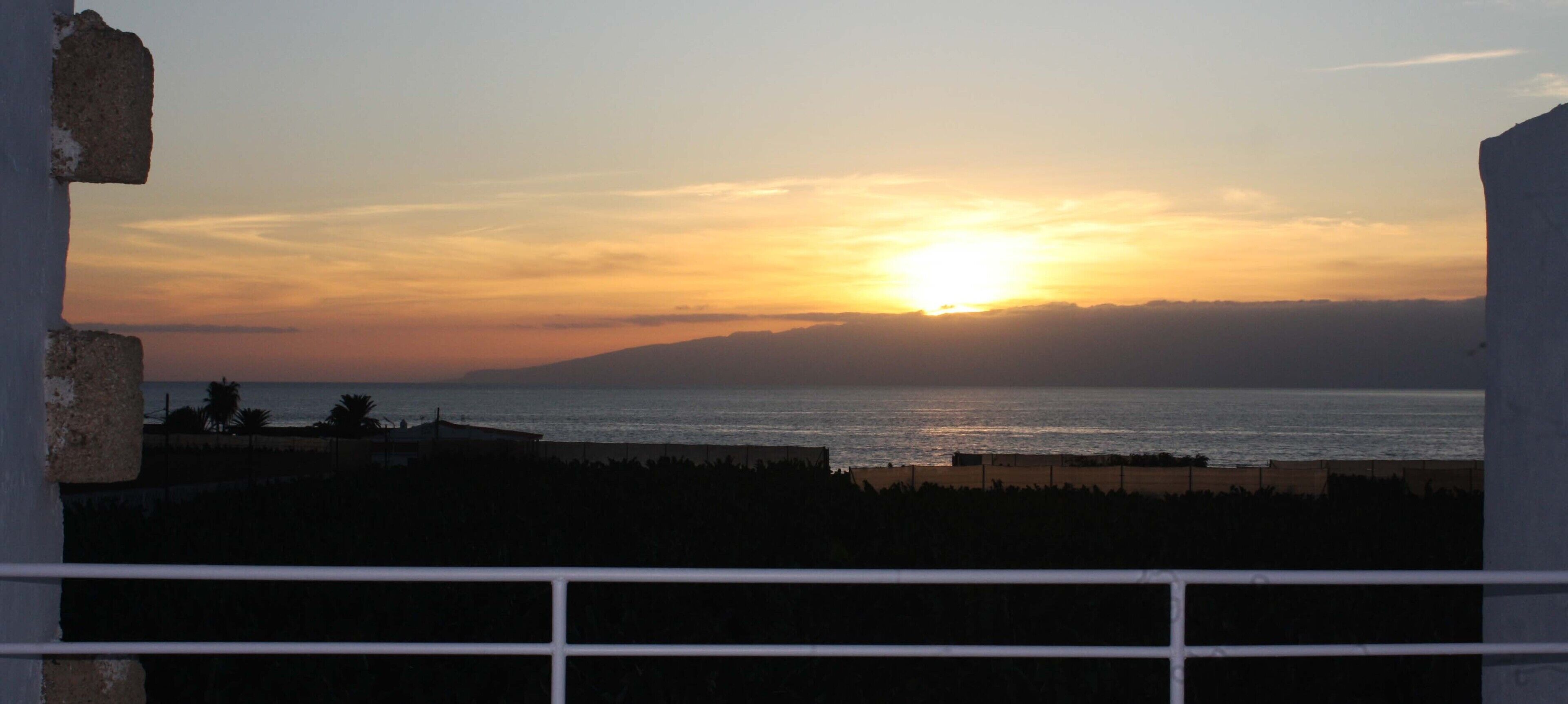 Un coucher de soleil sur une étendue d’eau, avec une masse terrestre visible au loin.