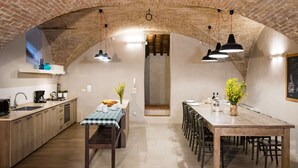 A rustic kitchen with exposed brick walls, a wooden dining table, and pendant lighting. - Appartamento La Corte (Cortona)