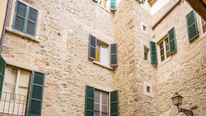 A courtyard with stone walls, green shutters, and potted plants. - Appartamento La Corte (Cortona)