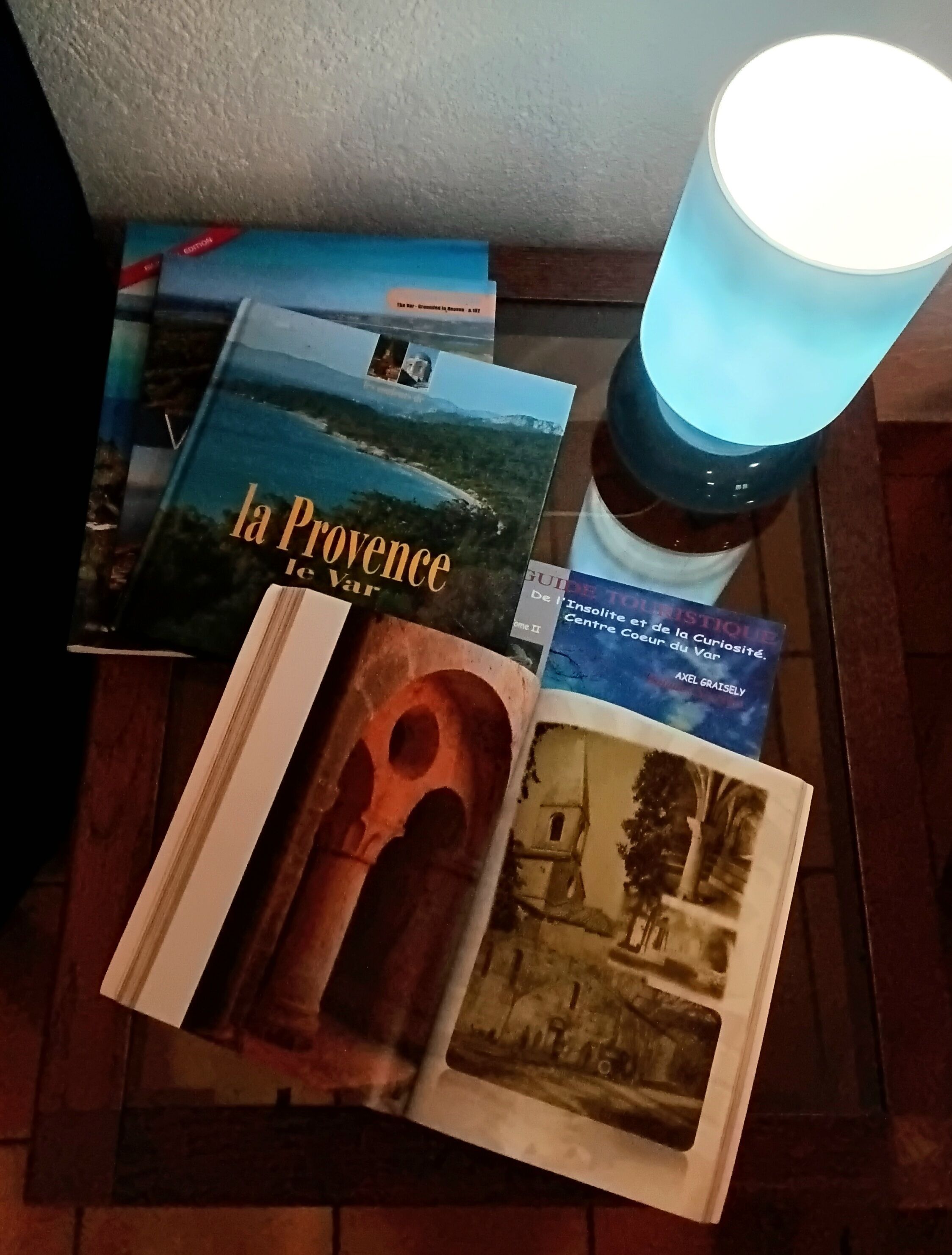 Una mesa con libros y un objeto cilíndrico, posiblemente un candelabro, con una luz azul.
