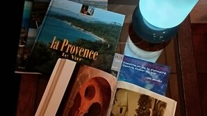 Ein Tisch mit Büchern und einem zylindrischen Gegenstand, möglicherweise einem Kerzenhalter, mit blauem Licht.