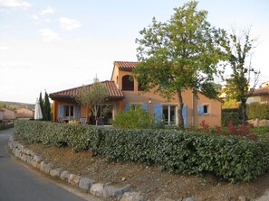 A Mediterranean-style house with a tiled roof, a stone wall, and a well-maintained garden.