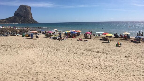 A beach with umbrellas and people.